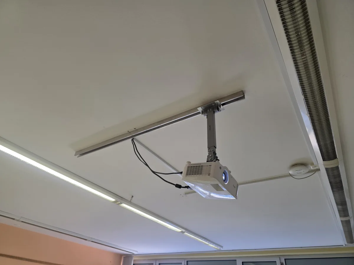 Projektor na nosilcu, pritrjenem na vodilo na stropu